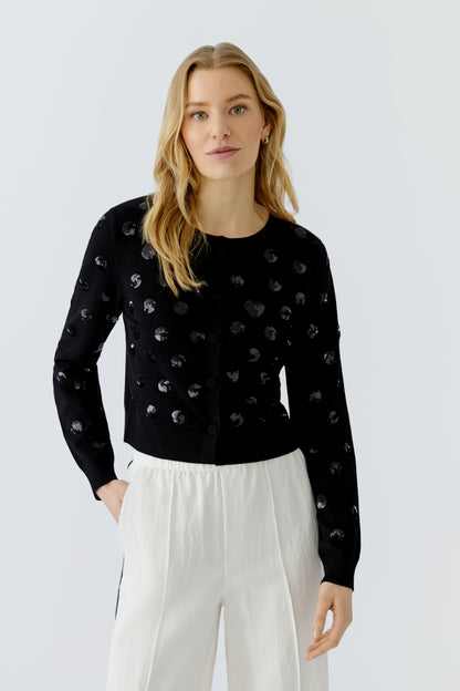 Woman wearing a black sweater with white patterns on a light gray background