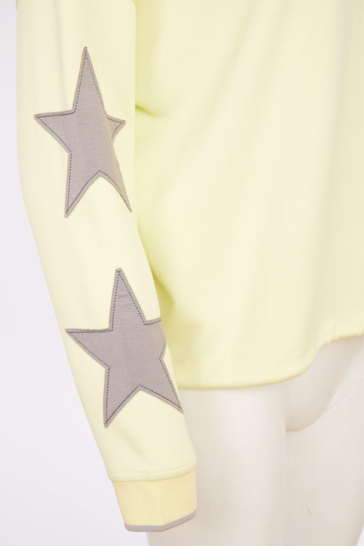 Yellow garment with gray star patterns on sleeves against a white background