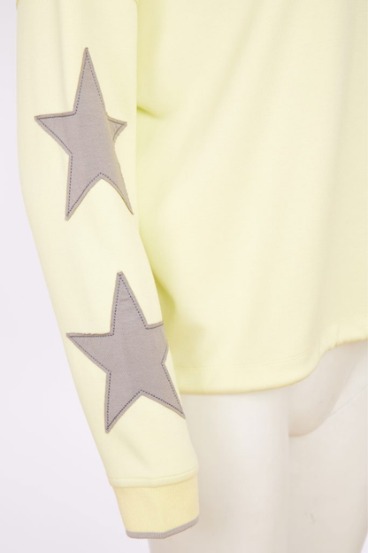 Yellow garment with gray star patterns on sleeves against a white background